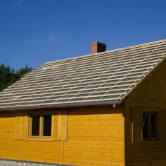 Dach drewnianego domu w budowie, przygotowany pod deskowanie pod blachodachówkę. Widać rusztowanie i komin.