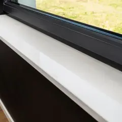 Biały parapet przy oknie antracyt. Wady okien antracyt mogą objawiać się zarysowaniami na ramie, co widać na zdjęciu.