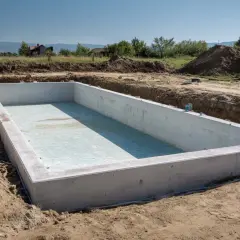 Betonowa niecka basenu wkopana w ziemię, gotowa do dalszych prac. Zastanawiasz się, ile kosztuje budowa basenu w ziemi?