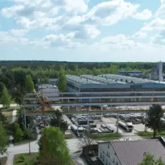 Fabryka domów Bogucin z lotu ptaka. Widok na hale produkcyjne, place składowe z elementami prefabrykowanymi i ciężarówki.