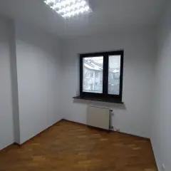 Puste pomieszczenie z drewnianą podłogą i oknem. Zastanawiasz się, ile trwa malowanie mieszkania?