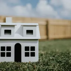 Model domu na trawie, symbolizujący minimalną wielkość działki budowlanej na wsi.