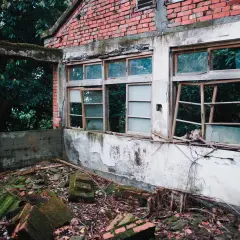 Opuszczony budynek z cegły, zniszczone okna i gruz na ziemi. Zastanawiasz się, gdzie wyrzucić szyby okienne?