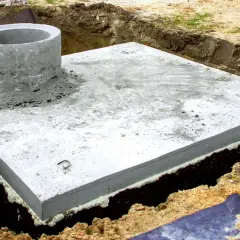 Betonowa płyta fundamentowa z kominem szamba, przygotowana do dalszych prac. Zastanawiasz się, ile kosztuje montaż szamba?