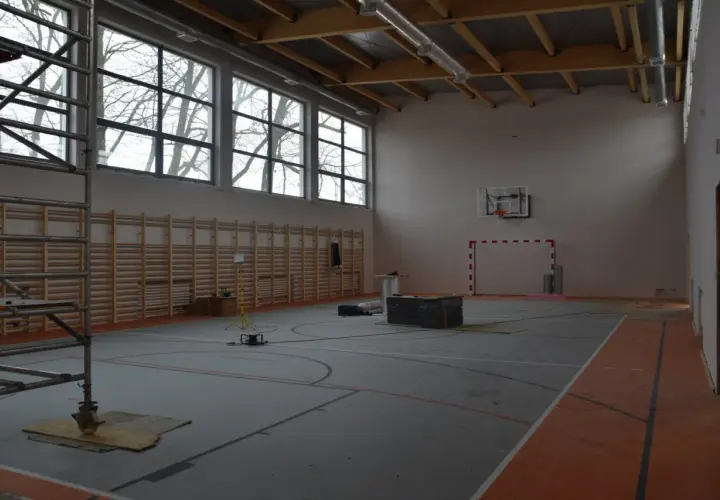 Wnętrze hali sportowej w budowie, z drabinkami, koszem i bramką. Zastanawiasz się, ile kosztuje budowa hali sportowej?
