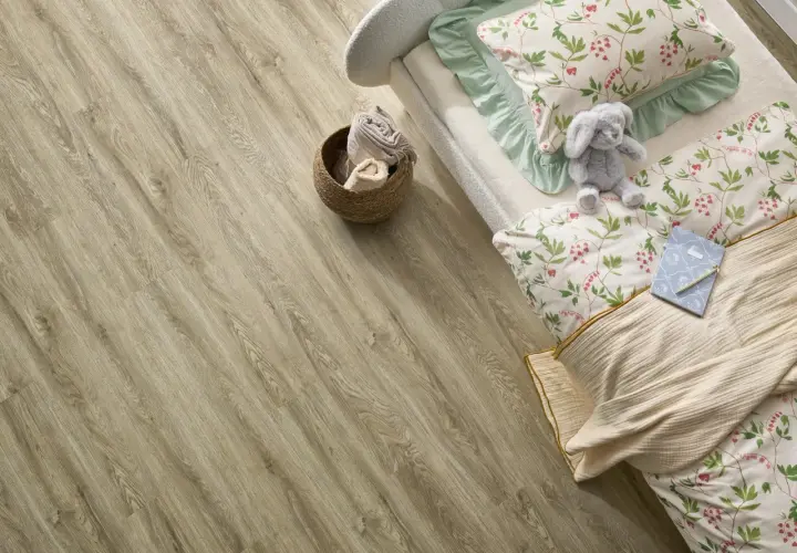 Łóżko z pluszowym królikiem i pościelą w kwiaty na podłodze z paneli winylowych. Czy panele winylowe są zdrowe? Tak, są bezpieczne dla dzieci.