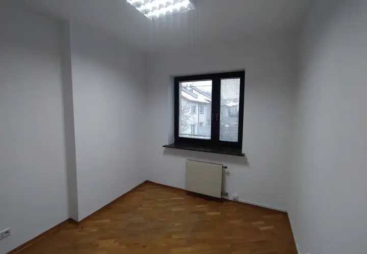 Puste pomieszczenie z drewnianą podłogą i oknem. Zastanawiasz się, ile trwa malowanie mieszkania?