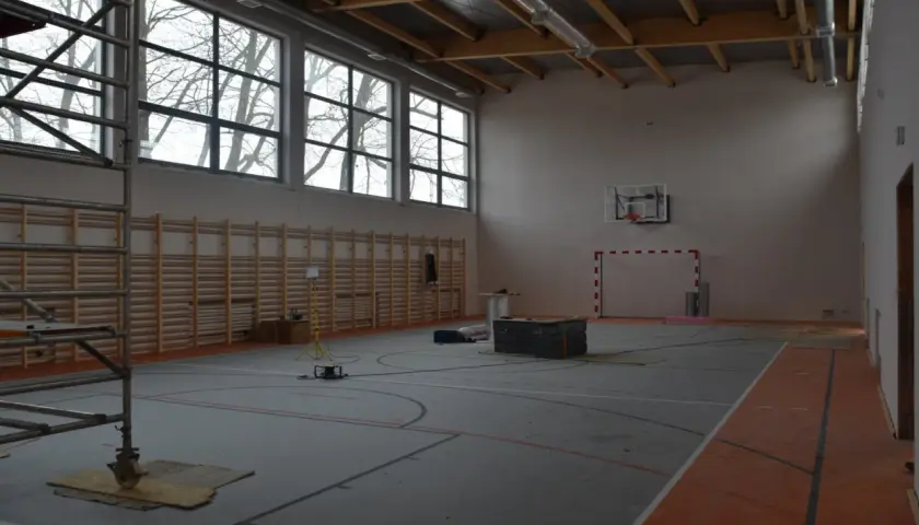 Wnętrze hali sportowej w budowie, z drabinkami, koszem i bramką. Zastanawiasz się, ile kosztuje budowa hali sportowej?