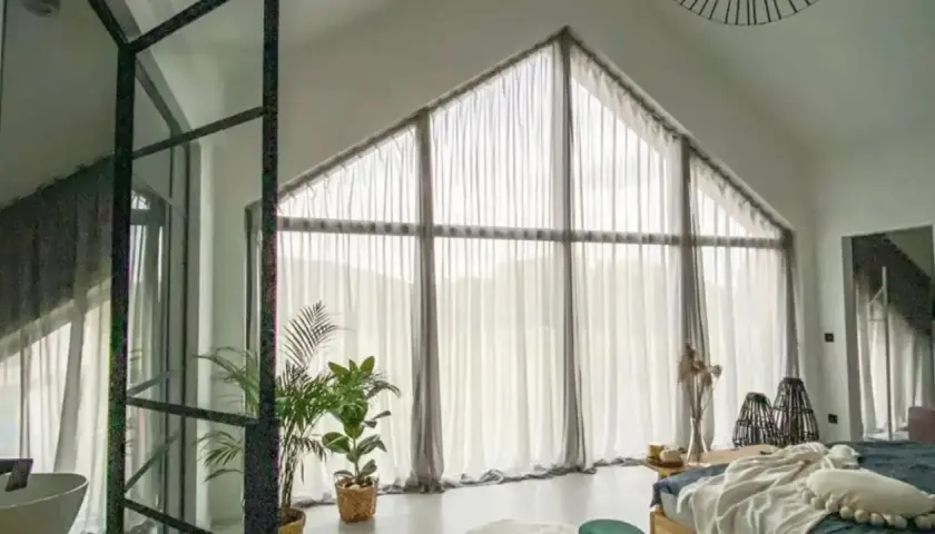 Zasłony z siateczki pięknie podkreślają, jak zasłonić okno trapezowe, tworząc przytulną atmosferę w sypialni.