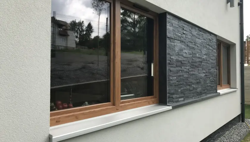 Nowoczesna elewacja z kamienną okładziną i drewnianymi ramkami okien.
