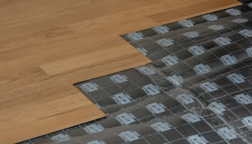 Układanie paneli podłogowych, pokazujące podkład i fragment gotowej podłogi. Dowiedz się, jak zakleić dziurę w panelu podłogowym.
