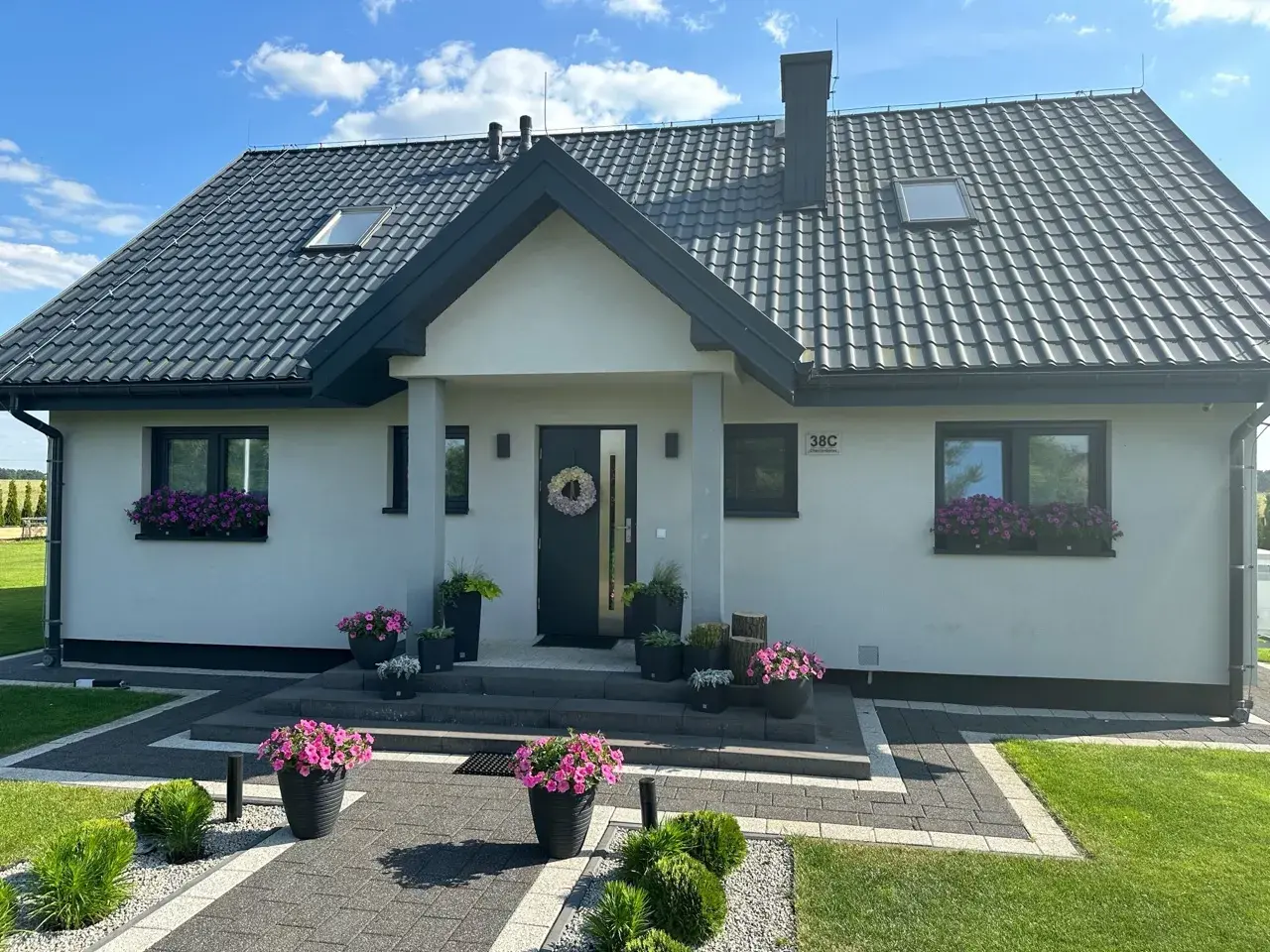Nowoczesny dom Kamilek 100m2 z pięknymi kwiatami w donicach i skrzynkach.