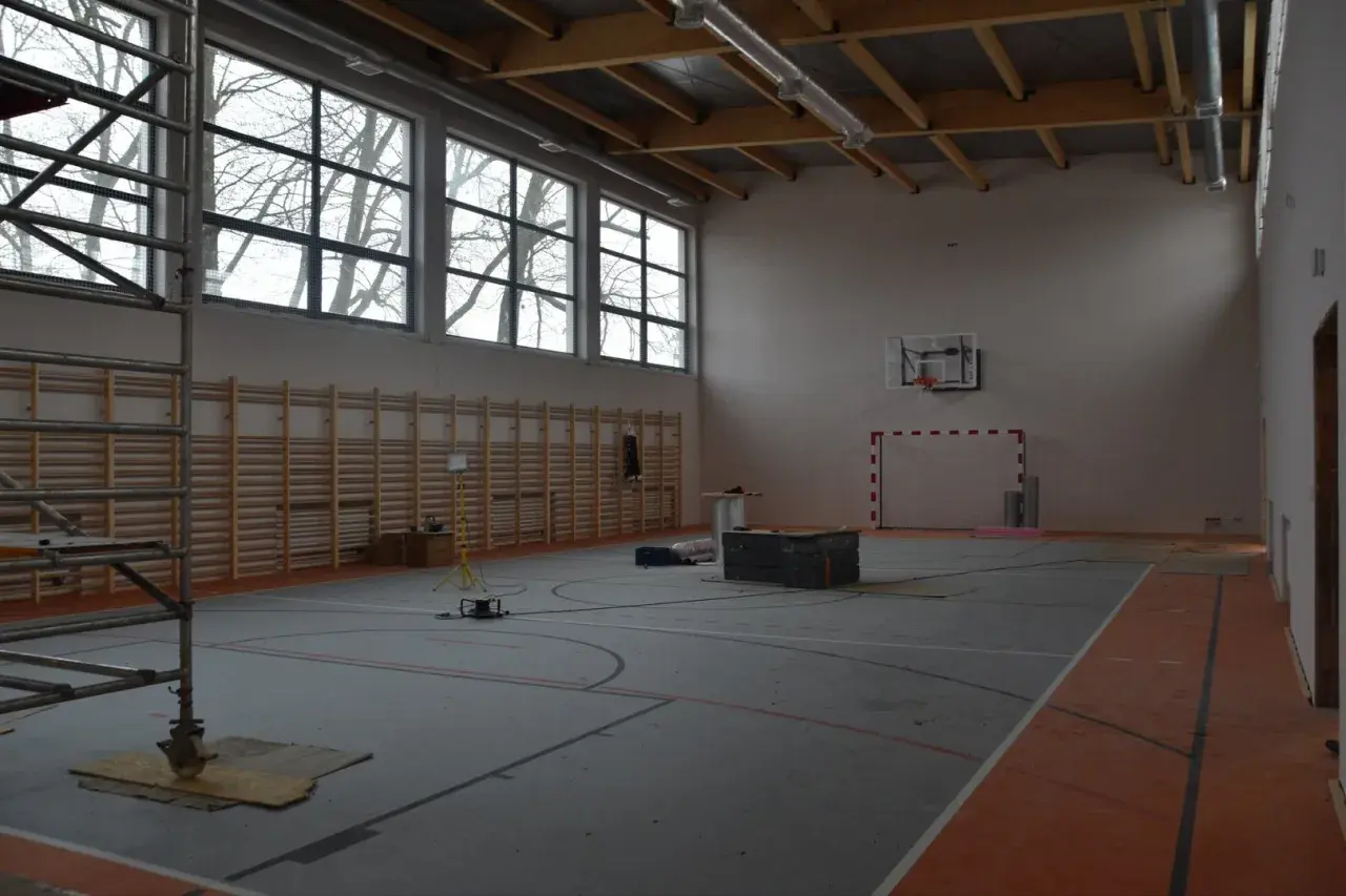 Wnętrze hali sportowej w budowie, z drabinkami, koszem i bramką. Zastanawiasz się, ile kosztuje budowa hali sportowej?