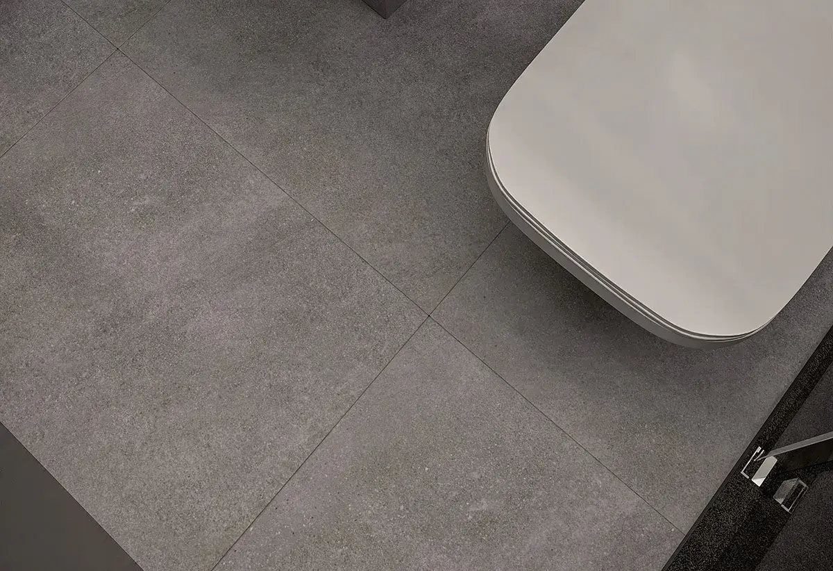 Nowoczesne wzory układania płytek 60x60 w łazience. Szare, wielkoformatowe płytki tworzą minimalistyczną bazę dla białej wanny.