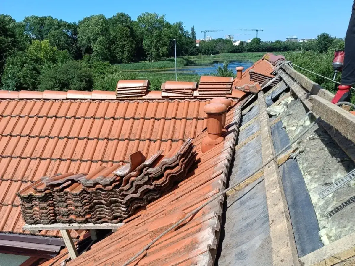 Układanie dachówek to kluczowy etap, jak naprawić dach z dachówki. Widoczna sterta dachówek czeka na montaż.