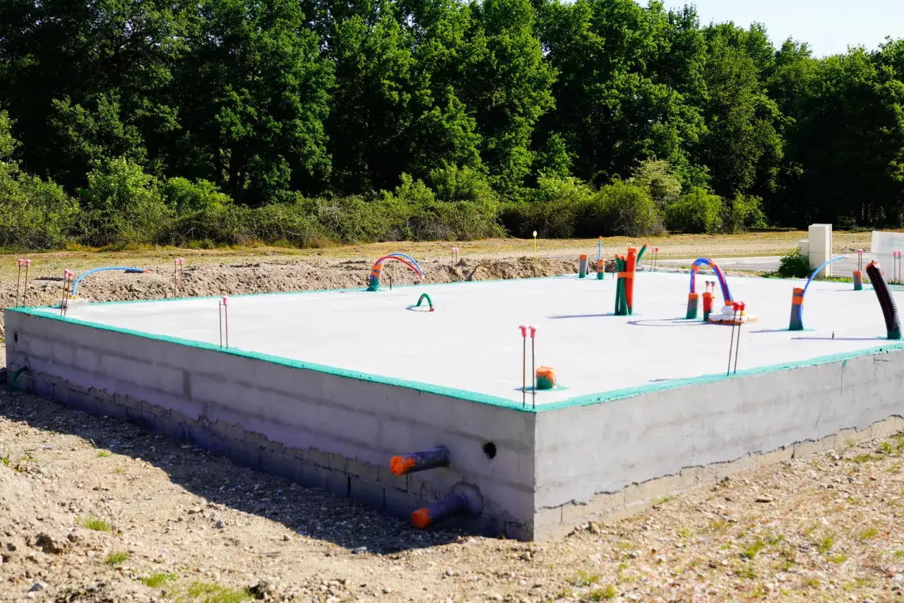 Płyta fundamentowa z instalacjami hydraulicznymi i elektrycznymi, gotowa do dalszych prac budowlanych. Zastanawiasz się, ile kosztuje płyta fundamentowa?