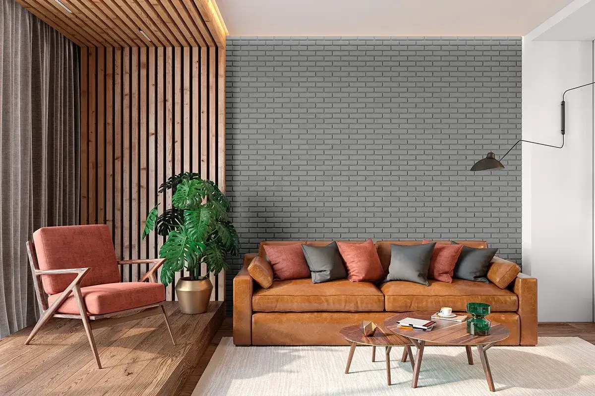 Nowoczesny salon z kanapą, fotelem i rośliną. Ściana za kanapą pokryta szarą farbą do cegły wewnątrz, tworząc industrialny klimat.